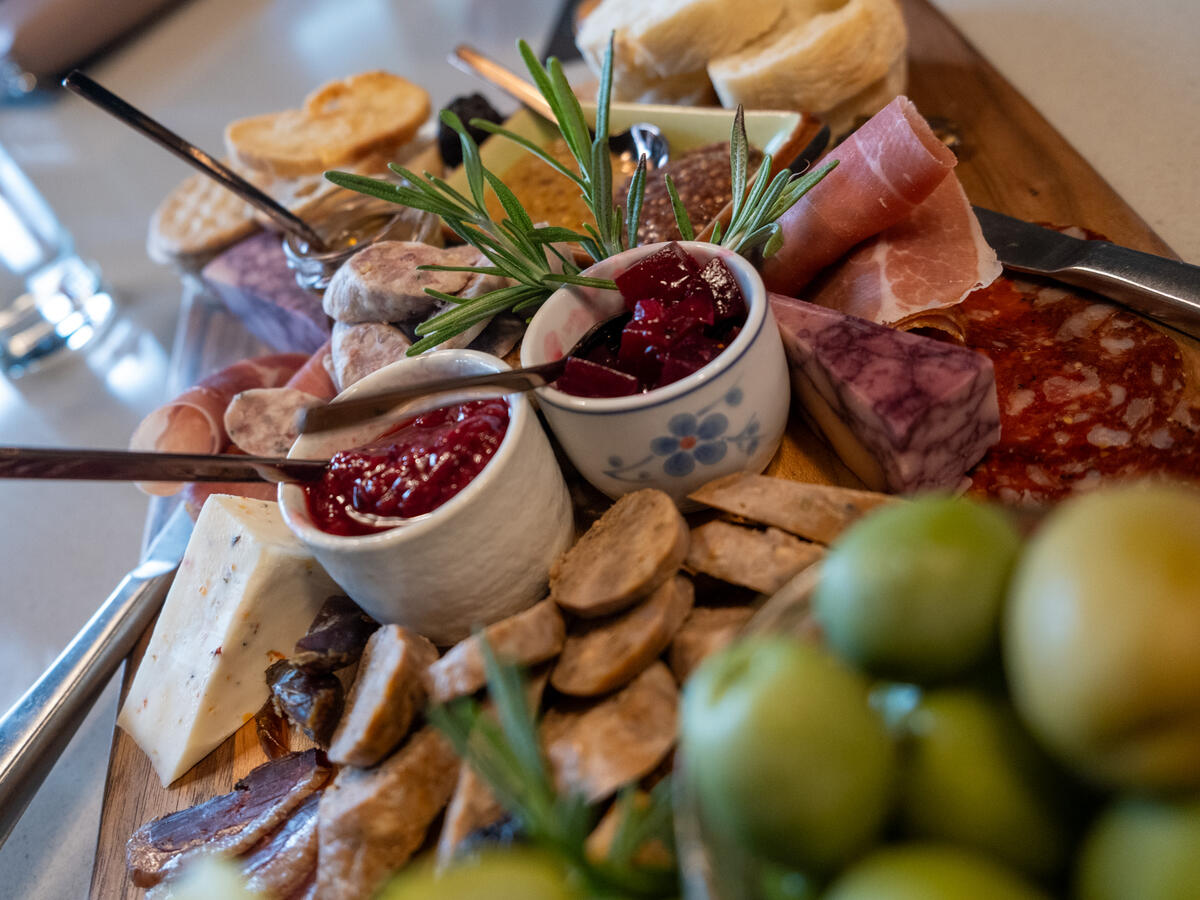 charcuterie board featuring olives, jams, sausage, and cheese